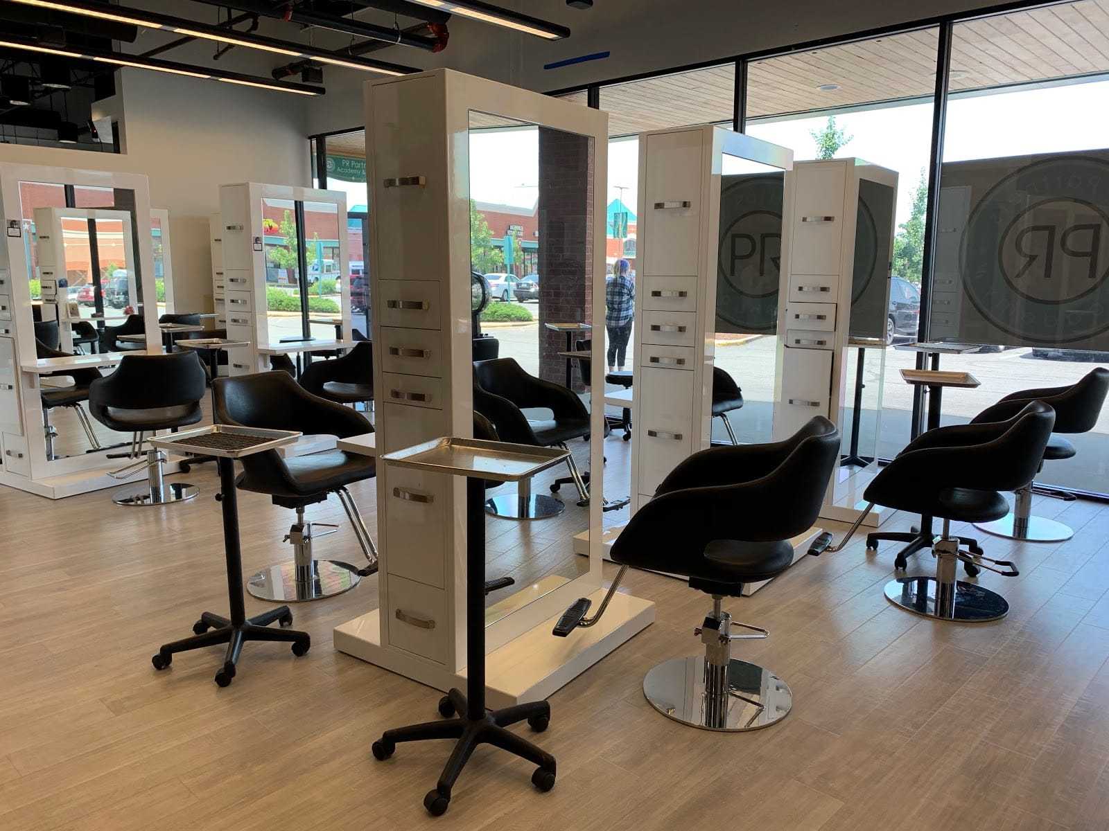 Modern salon interior with sleek black chairs, mirrors, and workstations.